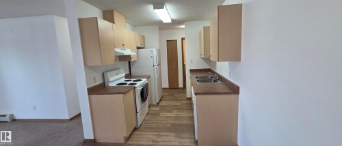 Well-maintained kitchen featuring light-colored cabinetry, laminate countertops, and essential appliances including a refrigerator, stove, and double sink - 208A 260 Spruce Ridge Road, Spruce Grove, AB - Indoor Photo Showing Kitchen With Double Sink