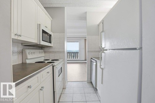 Kitchen featuring white cabinetry, a white electric range, a white microwave, and a white refrigerator - 604 9918 101 Street, Edmonton, AB - Indoor Photo Showing Kitchen
