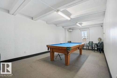 Recreational room featuring a billiards table with a blue felt surface, overhead fluorescent lighting, and a window providing natural light - 604 9918 101 Street, Edmonton, AB - Indoor Photo Showing Other Room