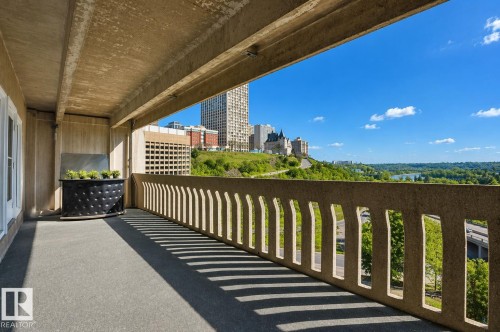 Expansive balcony with concrete flooring, a decorative planter, and a concrete railing providing views of the city skyline, distant river, and surrounding greenery - 604 9918 101 Street, Edmonton, AB - Outdoor With Exterior
