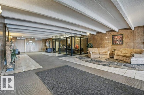 The property features a lobby with stone walls and textured ceilings, complemented by tiled and carpeted flooring - 604 9918 101 Street, Edmonton, AB -  Photo Showing Other Room