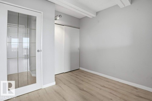 This room features light-toned wood flooring, light grey walls, and a white ceiling with exposed beams - 604 9918 101 Street, Edmonton, AB - Indoor Photo Showing Other Room