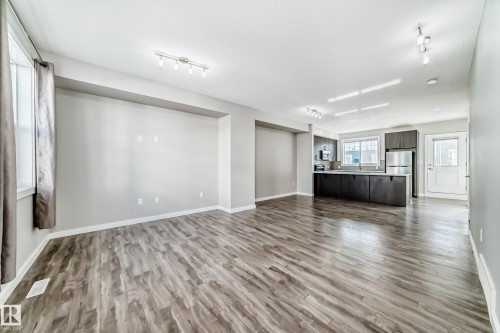 Open concept living space featuring wood-look flooring, light gray walls, and recessed lighting - 75 2803 James Mowatt Trail, Edmonton, AB - Indoor
