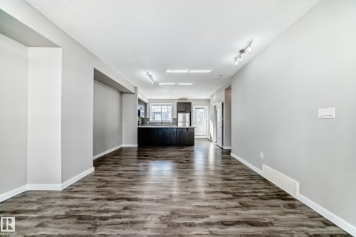 Open concept living space with wood-look flooring and light gray walls - 75 2803 James Mowatt Trail, Edmonton, AB - Indoor Photo Showing Other Room