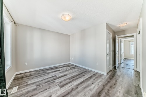This room features light grey walls and light-toned, wood-look flooring - 75 2803 James Mowatt Trail, Edmonton, AB - Indoor Photo Showing Other Room