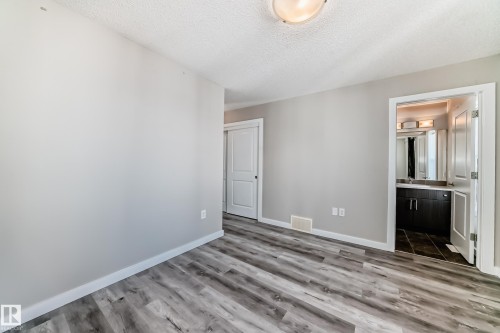 Room featuring light gray walls, gray wood-look flooring, a white baseboard, and a ceiling light fixture - 75 2803 James Mowatt Trail, Edmonton, AB - Indoor Photo Showing Other Room