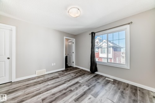 This room features light grey walls, a window with white trim, and a ceiling light fixture - 75 2803 James Mowatt Trail, Edmonton, AB - Indoor Photo Showing Other Room