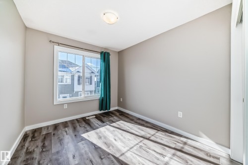 This room features light-colored walls, a window providing natural light, and dark wood-look flooring - 75 2803 James Mowatt Trail, Edmonton, AB - Indoor Photo Showing Other Room
