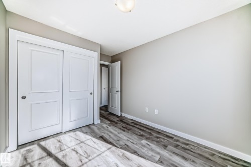 The room features light gray walls, wood-style flooring, and a ceiling light fixture - 75 2803 James Mowatt Trail, Edmonton, AB - Indoor Photo Showing Other Room
