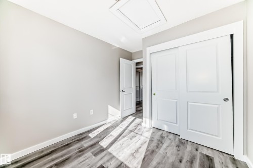 The room features light gray walls, wood-style flooring, and a white sliding closet door - 75 2803 James Mowatt Trail, Edmonton, AB - Indoor Photo Showing Other Room