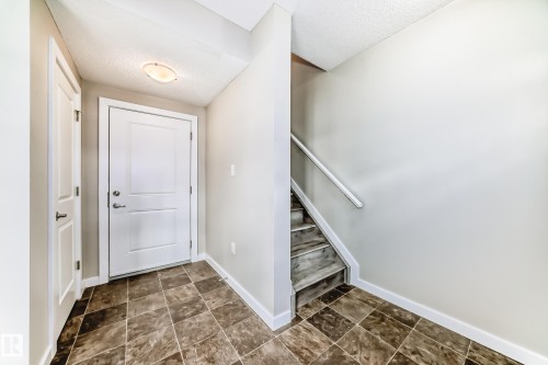 Entryway featuring tiled flooring, a white paneled door, and a staircase with a handrail - 75 2803 James Mowatt Trail, Edmonton, AB - Indoor Photo Showing Other Room