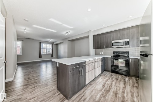 Open-concept kitchen and living area featuring wood-look flooring, recessed lighting, and windows providing natural light - 75 2803 James Mowatt Trail, Edmonton, AB - Indoor Photo Showing Kitchen With Upgraded Kitchen