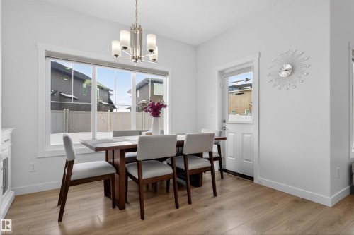 The dining area features hard surface flooring, a large window, and a chandelier with five lights - 7344 177 Avenue, Edmonton, AB - Indoor Photo Showing Dining Room