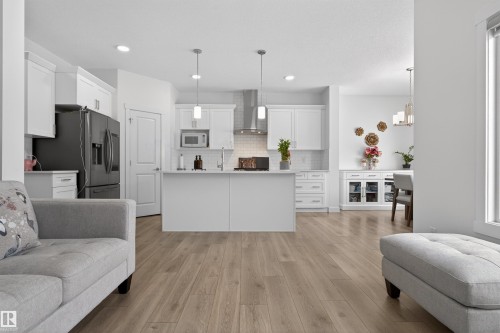 The kitchen features white cabinetry, a kitchen island, and a stainless steel range hood - 7344 177 Avenue, Edmonton, AB - Indoor