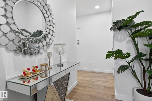 Entryway featuring light-colored flooring, a mirrored console table with a crushed glass detail, and a large circular wall mirror - 7344 177 Avenue, Edmonton, AB - Indoor Photo Showing Other Room
