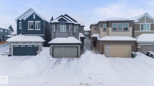 The property features a two-story design with a light brown and beige exterior, a two-car garage, and multiple windows - 7344 177 Avenue, Edmonton, AB - Outdoor With Facade