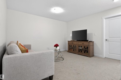 Living area featuring light-colored carpet flooring, white walls, and a white door with a silver handle - 7344 177 Avenue, Edmonton, AB - Indoor