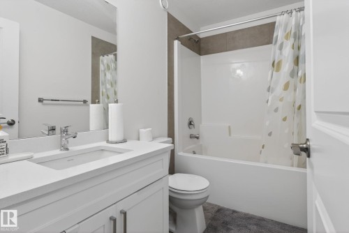Bathroom featuring a white vanity with a rectangular sink, a polished chrome faucet, and a shower-tub combination with tiled surround - 7344 177 Avenue, Edmonton, AB - Indoor Photo Showing Bathroom