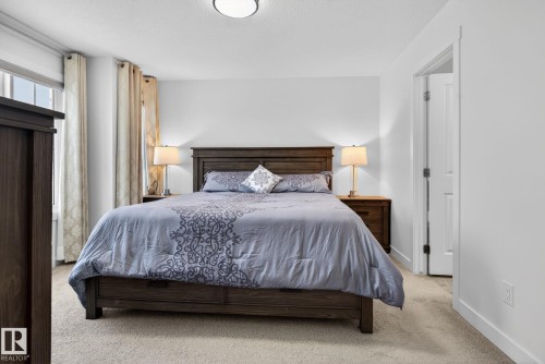 This bedroom features neutral-toned carpet, white walls, and a window with light-colored curtains - 7344 177 Avenue, Edmonton, AB - Indoor Photo Showing Bedroom