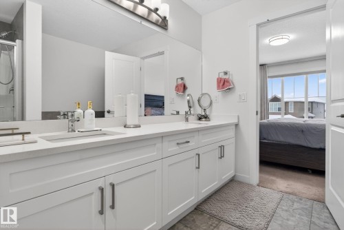 Bathroom featuring a double vanity with white cabinetry, light-colored countertops, and two chrome faucets - 7344 177 Avenue, Edmonton, AB - Indoor Photo Showing Bathroom