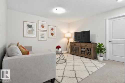 Living area featuring light-colored walls, a carpeted floor, and a white interior door - 7344 177 Avenue, Edmonton, AB - Indoor