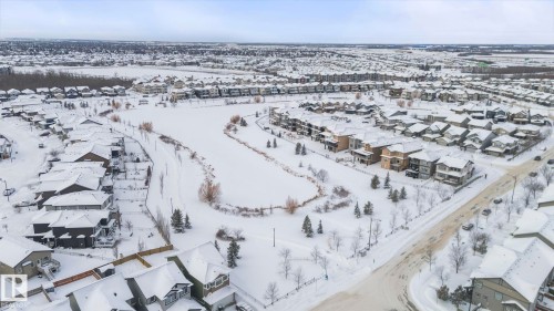 Aerial view of the neighborhood showcasing a large pond, extensive green spaces, and a variety of residential properties with snow-covered roofs - 7344 177 Avenue, Edmonton, AB - Outdoor With View