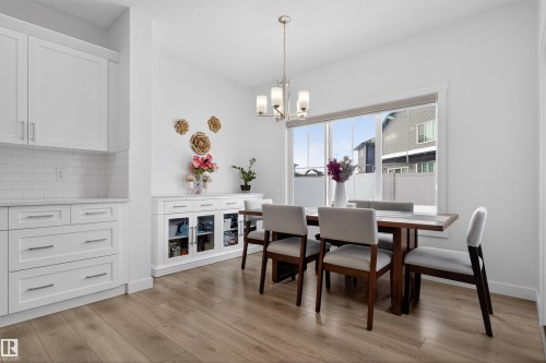 Dining area featuring light wood-style flooring, a large window, and a white cabinet unit with glass doors - 7344 177 Avenue, Edmonton, AB - Indoor Photo Showing Dining Room