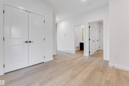 This interior space features light wood-look flooring, white walls, and white doors with dark hardware - 22 Meadowgrove Landing, Spruce Grove, AB - Indoor Photo Showing Other Room