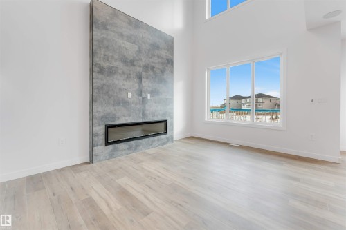 Living area featuring light-toned flooring, a floor-to-ceiling fireplace with a modern linear insert, and large windows providing ample natural light - 22 Meadowgrove Landing, Spruce Grove, AB - Indoor Photo Showing Living Room With Fireplace
