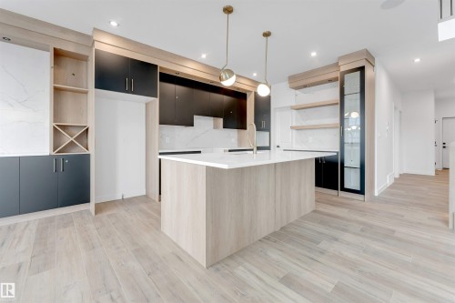 Contemporary kitchen featuring light wood-look flooring, a kitchen island with a white countertop, and dark cabinetry - 22 Meadowgrove Landing, Spruce Grove, AB - Indoor Photo Showing Kitchen