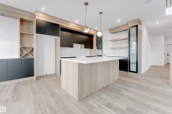 Contemporary kitchen featuring light wood-look flooring, a kitchen island with a white countertop, and dark cabinetry - 