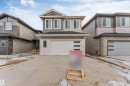 The property features a modern exterior with a mix of siding and stone accents, a prominent front-facing garage with frosted glass panels, and multiple windows across the facade - 22 Meadowgrove Landing, Spruce Grove, AB  - Outdoor With Facade 