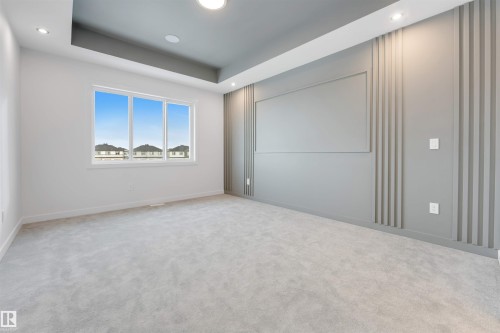 Spacious room featuring light-colored carpet flooring, a large window, and a tray ceiling with recessed lighting - 22 Meadowgrove Landing, Spruce Grove, AB - Indoor Photo Showing Other Room