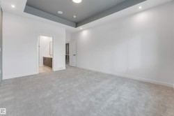 This spacious room features light grey carpeting, white walls, and a dropped ceiling with recessed lighting - 
