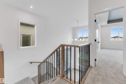 The property features a staircase with light wood handrails and black metal balusters, and a light-colored carpeted floor - 