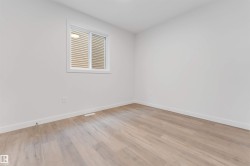 This room features light-toned wood flooring, white walls, and a window with blinds - 