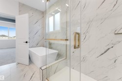 This bathroom showcases a freestanding tub and a glass-enclosed shower with gold-toned hardware - 