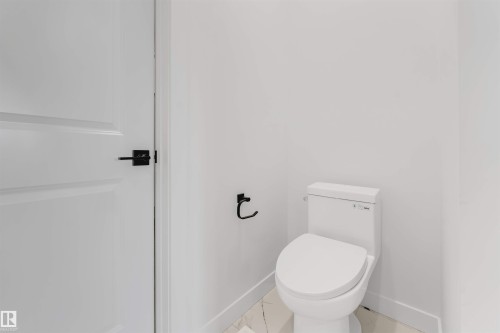 The bathroom features a modern toilet, white walls, and a white paneled door with matte black hardware - 22 Meadowgrove Landing, Spruce Grove, AB - Indoor Photo Showing Bathroom
