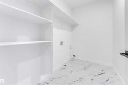 Utility room featuring white walls, white shelving, and tile flooring - 