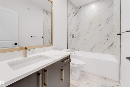 Contemporary bathroom featuring a vanity with a rectangular sink, a gold-toned faucet, and dark cabinetry with gold-toned handles - 22 Meadowgrove Landing, Spruce Grove, AB - Indoor Photo Showing Bathroom