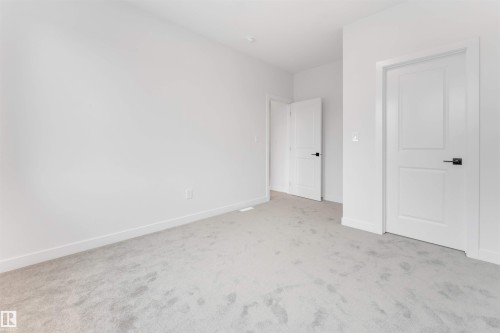 The room features light gray carpeting and white walls, offering a neutral palette - 22 Meadowgrove Landing, Spruce Grove, AB - Indoor Photo Showing Other Room