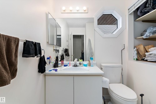 The bathroom features a white vanity with an integrated sink, a mirror with medicine cabinet storage, and an octagonal window - 5737 189 Street, Edmonton, AB - Indoor Photo Showing Bathroom