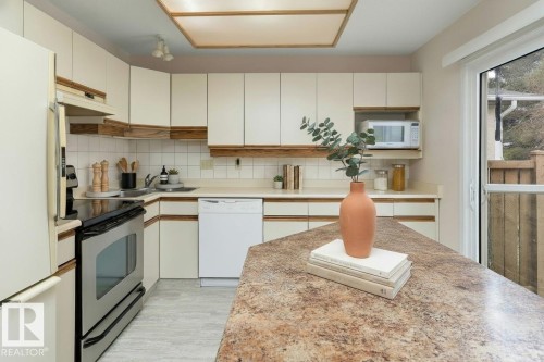 The kitchen features light-colored cabinetry, a corner sink, and a stainless steel range - 5737 189 Street, Edmonton, AB - Indoor Photo Showing Kitchen