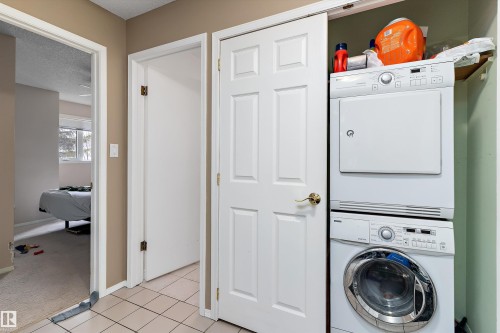Laundry area featuring a stacked washer and dryer unit, and tiled flooring - 5737 189 Street, Edmonton, AB - Indoor Photo Showing Laundry Room