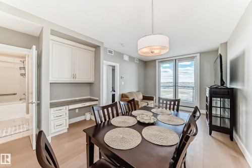 The open concept living area features light-colored flooring, a modern drum pendant light fixture, and large patio doors providing ample natural light - 506 11080 Ellerslie Road, Edmonton, AB - Indoor Photo Showing Dining Room