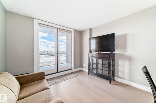 The living area features light-colored flooring and a patio door that opens to an outdoor space - 506 11080 Ellerslie Road, Edmonton, AB - Indoor
