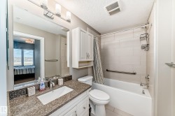 This bathroom features a vanity with a speckled countertop, an integrated sink, and white cabinetry - 