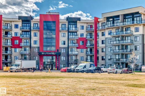 This multi-story building features a contemporary design with red and beige facade elements - 506 11080 Ellerslie Road, Edmonton, AB - Outdoor With Balcony With Facade