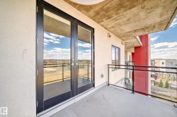 The property features an outdoor balcony with a concrete floor and a glass railing with a black metal frame - 