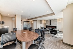 The property features a dedicated meeting area with a large oval table and chairs, complemented by a lounge space with armchairs and a modern fireplace set into a tiled wall - 